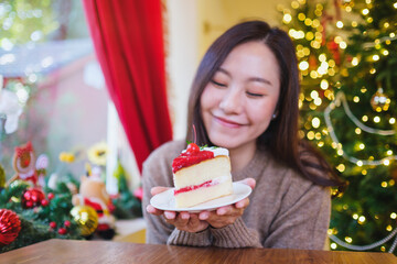 Portrait image of a woman holding a piece of cherry cake in Christmas holidays