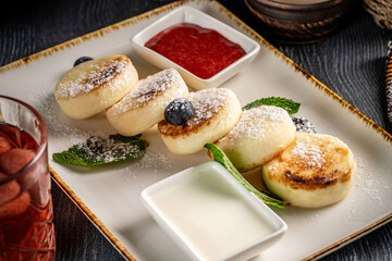 Fresh syrniki with powdered sugar and berry sauce