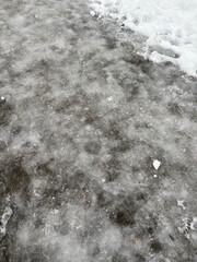 Icy pavement covered with snow posing danger for walking and driving  
