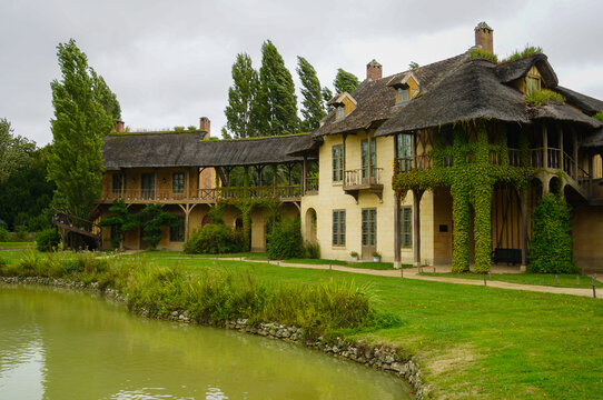 The Hameau de la Reine at Trianon, Marie Antoinette&rsquo;s pastoral estate with charming rustic cottage buildings, landscaped flower gardens, showcasing  historic elegance and beauty of French countryside