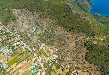 Kayakoy, Turkey. Aerial panoramic photograph of extensive ghost town ruins sprawling across mountain hillsides with Mediterranean landscape in background. Aerial view