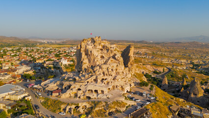 Uchisar, Nevsehir, Turkey. Morning aerial view of the majestic Uchisar Castle rock fortress and traditional cave houses in surrounding village.. Aerial View