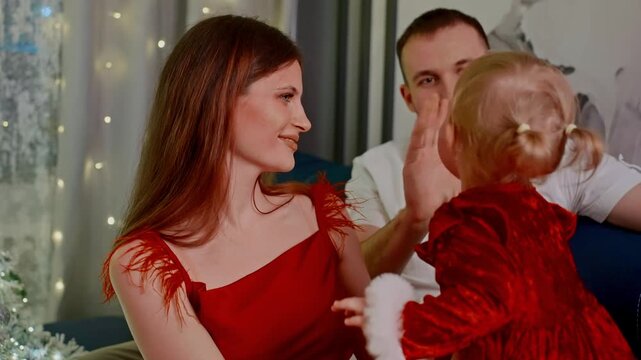 joyful family sharing affectionate gestures near holiday decorations, cheerful household embrace featuring decorative tree and glowing fairy lights during festive season