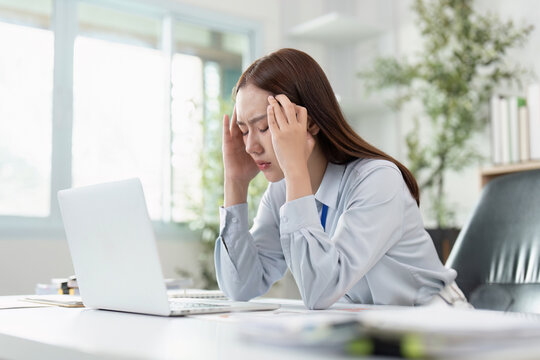 Travel Planning Headache. A woman with a headache while organizing her travel plans at a desk.