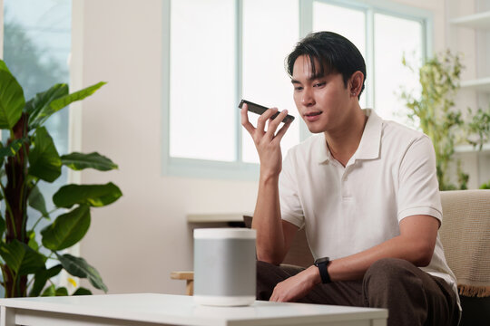 Smart Technology. A man using voice commands with smart speaker at home.