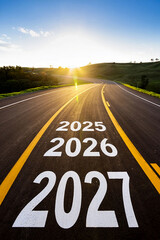 Road ahead with 2025 2026 2027 painted on asphalt towards sunset