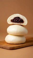 Stack of sweet red bean filled steamed buns on a wooden board
