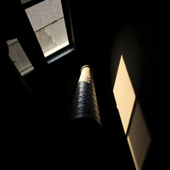 This image captures a dramatic interplay of light and shadow within a dark, possibly interior architectural space. Strong, directional light filters through unseen openings, creating distinct geometri