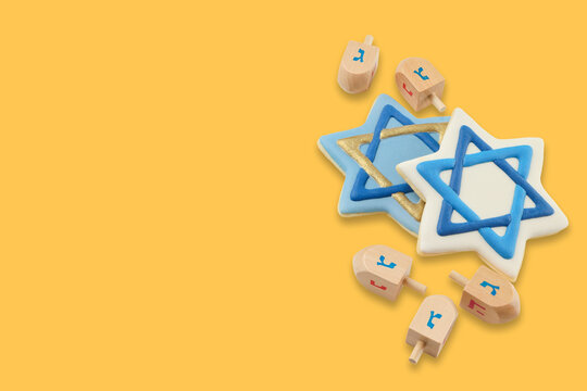 Hanukkah stars of David and wooden dreidels arranged on yellow