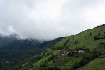 Fototapeta premium Mountain Village on Green Hillside under Cloudy Sky in Sa Pa, Vietnam