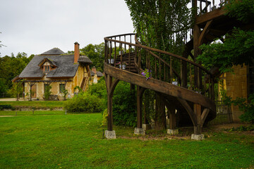 The Hameau de la Reine at Trianon, Marie Antoinette’s pastoral estate with charming rustic cottage buildings, landscaped flower gardens, showcasing  historic elegance and beauty of French countryside © faestock