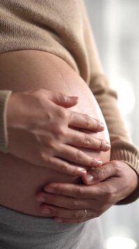 Happy pregnant woman or mother touching baby in belly with love at home. Health care, Prenatal preparation, Maternity, Pregnancy, and motherhood concept