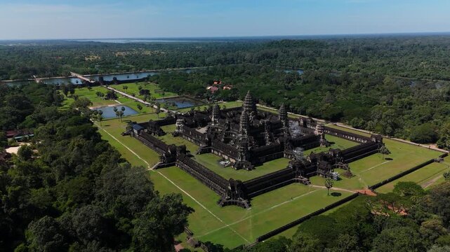 An ascending pull-back aerial shot reveals Angkor Wat and its surrounding landscape, showcasing the temple&rsquo;s full layout and forested setting