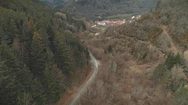 Drone footage returning from a valley path towards Isaba village under grey skies and early spring colors.