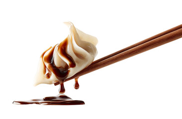 A delicate dumpling is dipped in rich, dark sauce with chopsticks