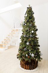 白い部屋と階段、黒と白のオーナメントで飾られたおしゃれなクリスマスツリー