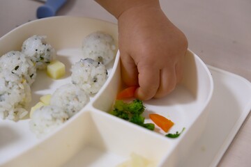 Baby's Hand Grabbing Rice Ball (Onigiri) in a Divided Plate (Japanese Finger Food Weaning and Self-Feeding)