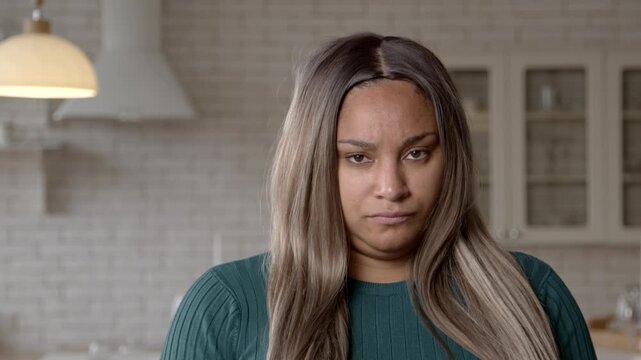 Portrait of displeased attractive chubby black woman standing with arms crossed , listening to excuses , expressing disbelief, frustration and anger in domestic room.