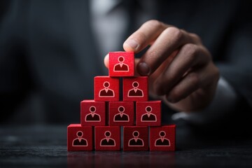 Hand placing final red block on human resource pyramid structure.