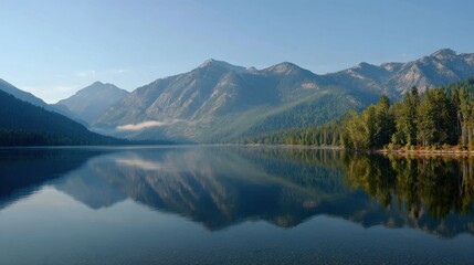 Fototapeta premium Early morning reveals a tranquil lake surrounded by majestic mountains. The still water perfectly mirrors the peaks and trees creating a serene landscape.