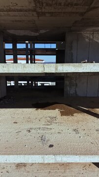 Dust and debris scatter the unfinished floor of a construction site, where rusty rods rest beside a dark patch, hinting at the ongoing efforts to shape the future of this urban landscape.