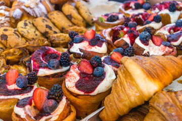 Assorted pastries with cream and fresh berries on the bakery counter. Close-up of sweet desserts. 