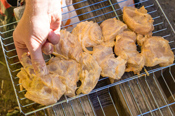 Chicken cooks on a portable grill by a lake during a hiking and outdoor travel stop. 