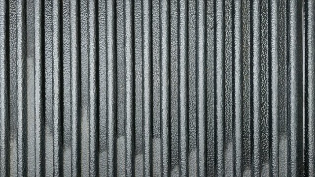 Black truck bed liner with deep vertical grooves. The surface is rough, durable, and wet-damp. Ideal as an industrial background or for use as a surface pattern.