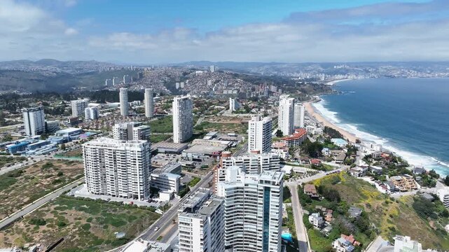 Orbiting drone aerial of Vi&ntilde;a del Mar high-rise coastal towers, Pacific Ocean beaches, bay panorama, and mountain backdrop, Chile resort city