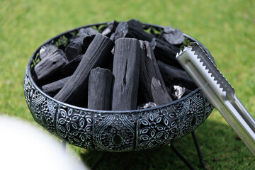 火起こし前の高級炭とトング、芝生を背景に