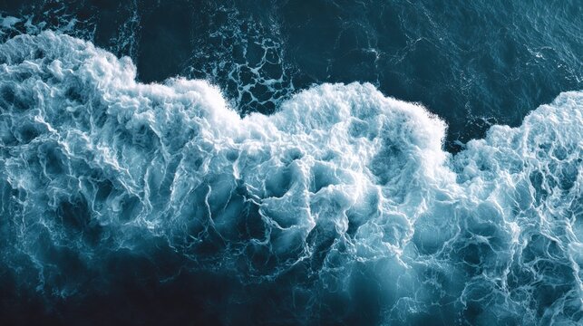 Aerial view of a powerful ocean wave crashing with foamy white water.