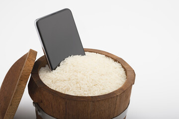 A wet smartphone is dried in rice bucket on white background , Tips and tricks idea for everyday life concept