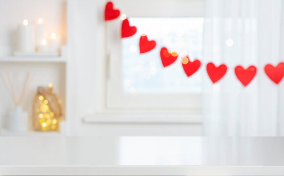 Holiday mock up for design and product display with empty white table on decorated with red hearts blurred window interior background