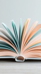 Naklejka premium Open book with pastel colored pages fanned out on a neutral background.