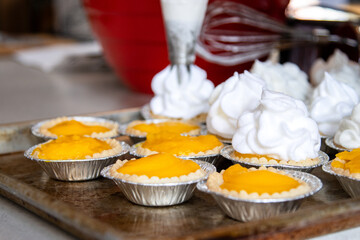 Piping swirled meringue onto lemon curd tarts on baking tray