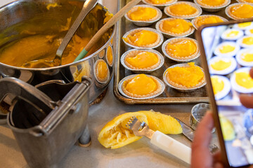 Person photographing lemon tarts filled with curd on tray