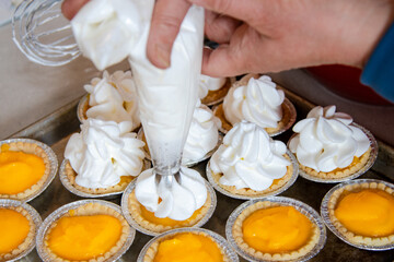 Piping fresh meringue onto lemon tarts in home kitchen