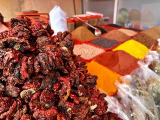 Piles of dried red peppers and vibrant spices at a market stall