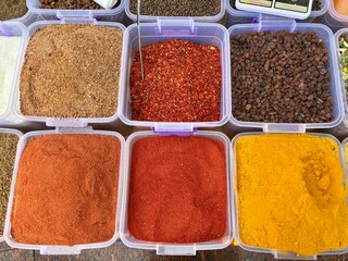 Assortment of vibrant ground spices and dried fruits at a market stall