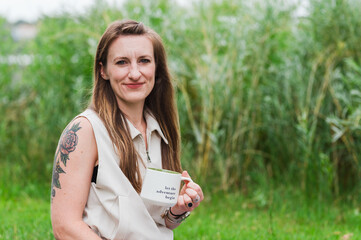 Obraz premium Woman holding inspirational coffee mug while sitting outside