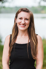 Smiling woman in black tank top near water