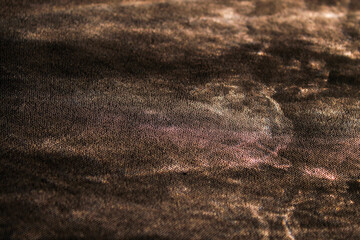 Black cloth with warm golden yellow light with patterns in the shadows