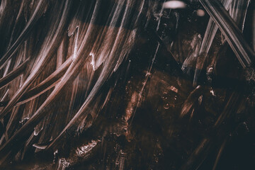 Dark abstract texture with scratches, stains and random patterns in brown and white.