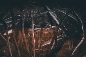 Dark abstract texture with scratches, stains and random patterns in brown and white.