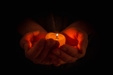 Hand holding burning candle in dark background. Selective focus,black background. Copy space.