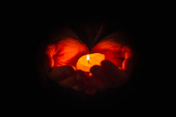 Hand holding burning candle in dark background. Selective focus,black background. Copy space.