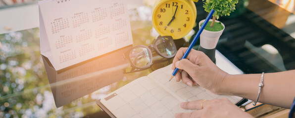 Close up of Female hand planner or organizer writing appointment on 2017 Calendar page.Woman mark and noted schedule on book or diary at office desk.Calendar reminder event concept.