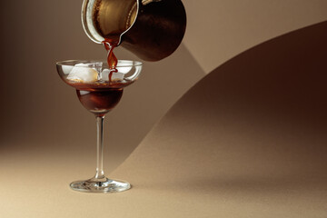 Black coffee is poured into a glass with ice.