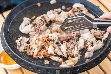 Sliced meat being grilled on a pan, creating a savory and appetizing cooking scene.