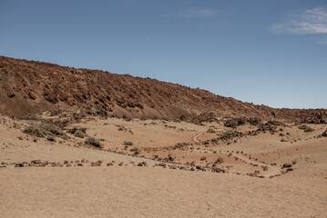 A path meanders through a barren landscape on Tenerife, lined with scattered rocks, evoking a sense of calm amidst the rugged scenery
